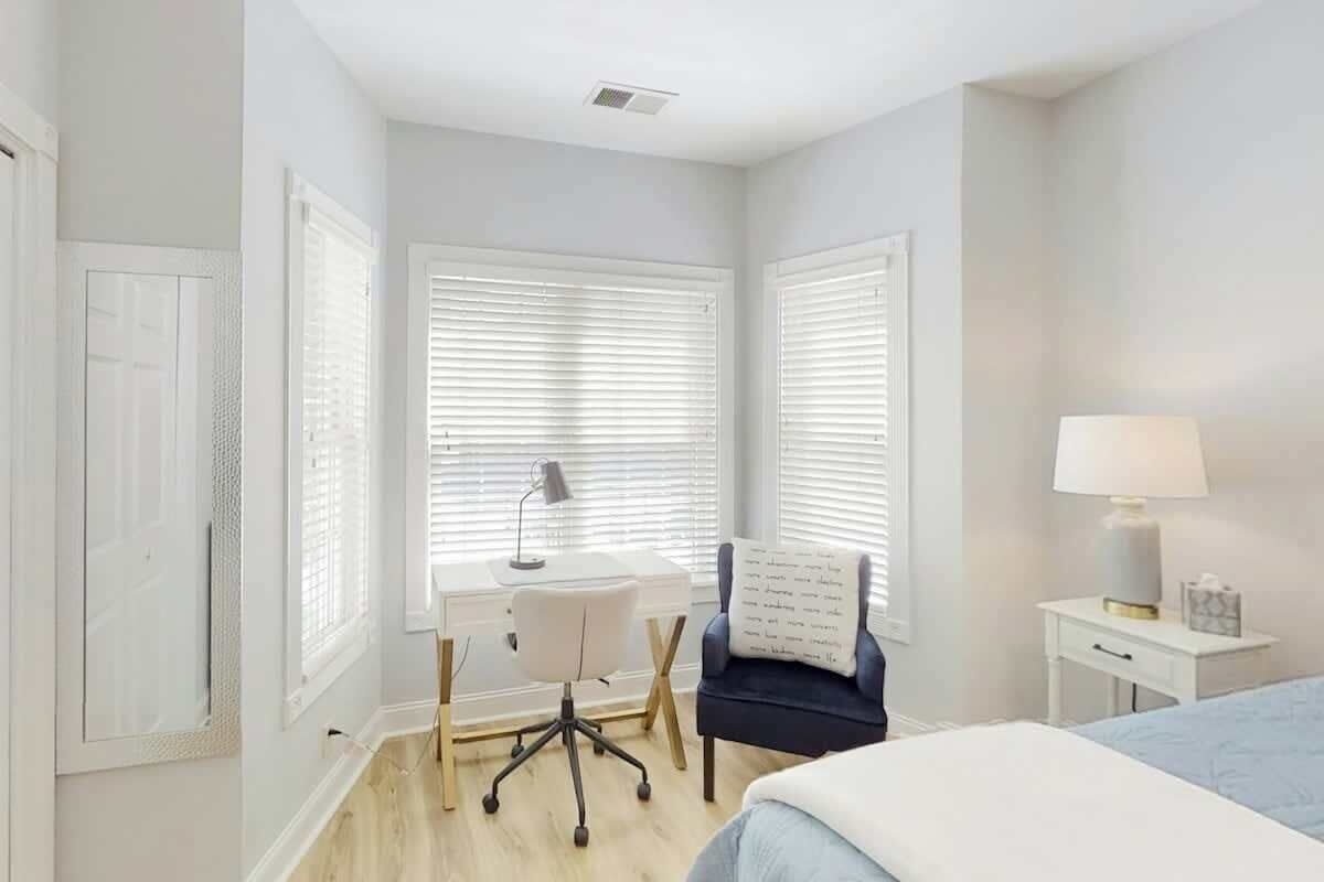 A bedroom with a bed, a desk, a chair, and a nightstand.