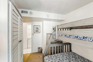 A room with bunk beds, a door, a trash can, and a framed picture on the wall. - The Summit Unit 2-A Condo (North Myrtle Beach)