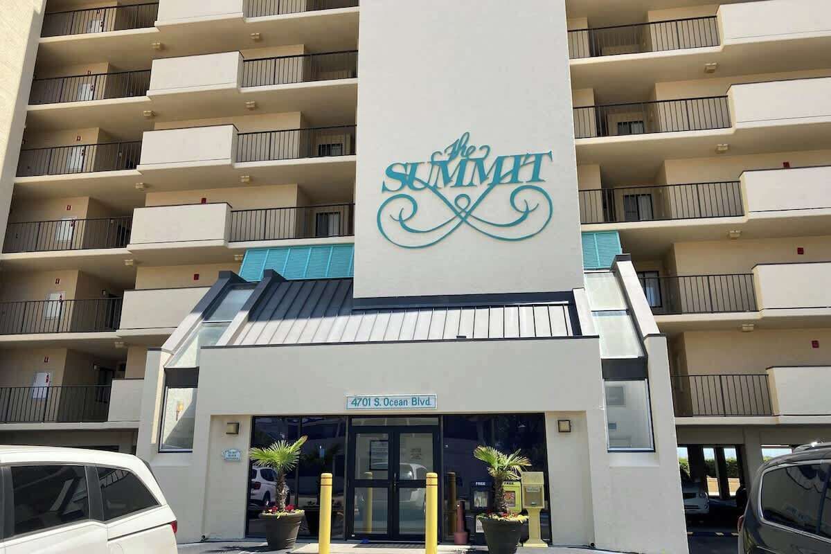 Ein mehrstöckiges Hotel mit Balkonen, eine auffällige Schilder mit der Aufschrift 'The Summit' und ein Schild mit der Adresse '4701 S. Ocean Blvd.'