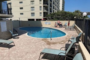 A pool area with lounge chairs and a sign indicating pool rules. - The Summit Unit 2-A Condo (North Myrtle Beach)