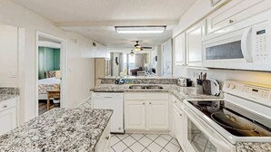 A kitchen with white cabinets, a microwave, an oven, and a granite countertop. - The Summit Unit 2-A Condo (North Myrtle Beach)
