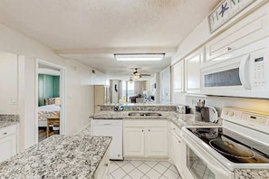A kitchen with white cabinets, a microwave, an oven, and a granite countertop. - The Summit Unit 2-A Condo (North Myrtle Beach)