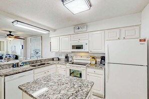 A kitchen with white cabinets, a microwave, stove, and refrigerator. - The Summit Unit 2-A Condo (North Myrtle Beach)