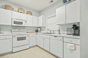 A modern kitchen with white cabinetry, a microwave, stove, and dishwasher. - Cypress Bend Unit 222 (North Myrtle Beach)