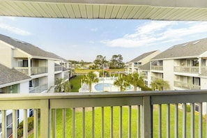 A view of a residential building with multiple balconies, a swimming pool, and a landscaped area with trees. - Golf Colony at Deerfield 26H (Surfside Beach)