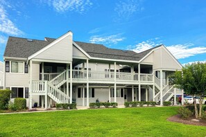 A two-story residential building with a covered front porch and a staircase leading to the upper level. - Golf Colony at Deerfield 26H (Surfside Beach)