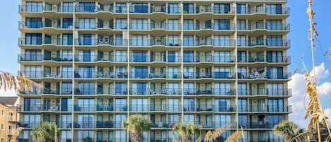 A multi-story hotel with balconies, a flat facade, and a clear sky.