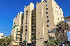 A multi-story hotel with balconies, a sign reading 'Beach Club III,' and a parking area with cars. - Beach Club III Unit 8-D (North Myrtle Beach)