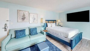 A bedroom with a bed, a sofa, a nightstand, and wall art. - Bay Watch Resort 0801 (North Myrtle Beach)