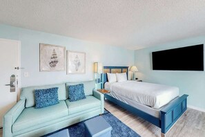 A bedroom with a bed, a sofa, a nightstand, and wall art. - Bay Watch Resort 0801 (North Myrtle Beach)