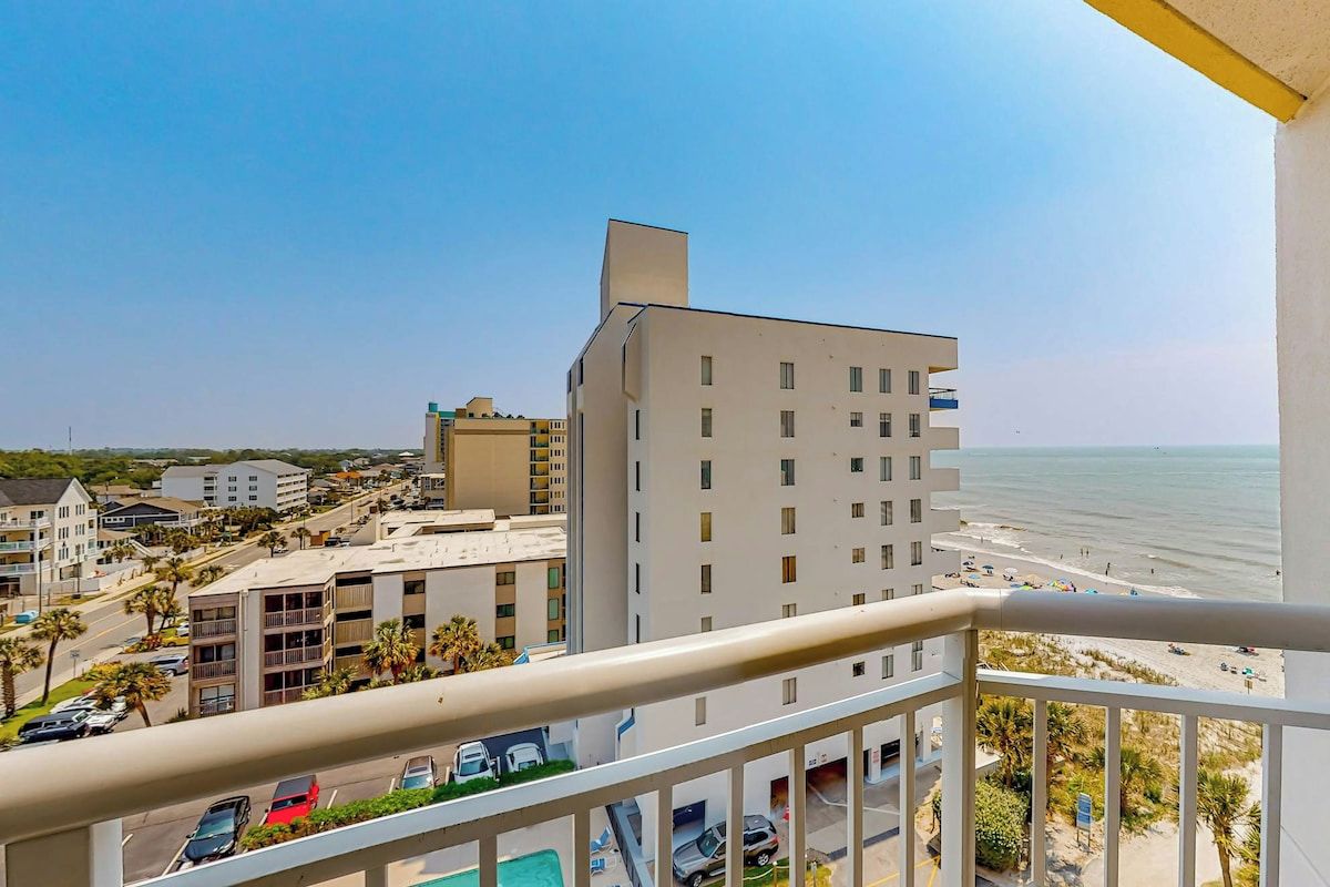 A high-rise building with a balcony overlooking a beach and ocean.