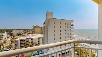 A high-rise building with a balcony overlooking a beach and ocean.