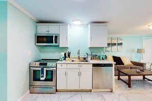 A compact kitchen with a built-in oven, microwave, and dishwasher. There is a dining area with a table and a sofa. - Flamingo House 1 - bottom (North Myrtle Beach)
