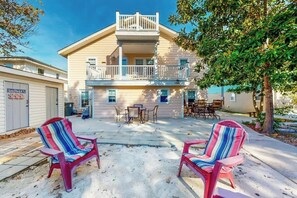 A two-story building with a balcony, outdoor seating area, and a sign indicating a shower facility. - Flamingo House 1 - bottom (North Myrtle Beach)