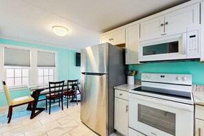 La cuisine est équipée d’un réfrigérateur en acier inoxydable, d’un four à micro-ondes et d’un four traditionnel. On y trouve également une table à manger avec des chaises.