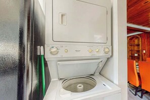 A compact, white washing machine with a front-loading door, a control panel with multiple dials, and a small circular drum. - Flamingo House Retreat (North Myrtle Beach)