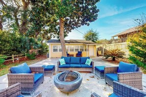 A backyard with wicker furniture, a fire pit, and a house in the background. - Flamingo House Retreat (North Myrtle Beach)