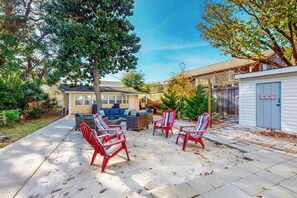 Ein Garten mit Terrasse, Gartenmöbeln und einem überdachten Bereich.