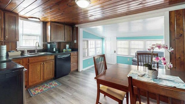 Una cocina con armarios de madera, una mesa de comedor con sillas y vistas al exterior.