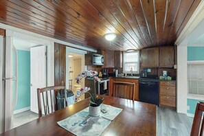 A wooden-paneled kitchen with a dining table, chairs, and a potted orchid. - Flamingo House Retreat (North Myrtle Beach)