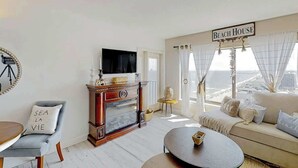 Ett vardagsrum med en tv, en soffa, ett soffbord och en skylt med texten ”Strandhus”.