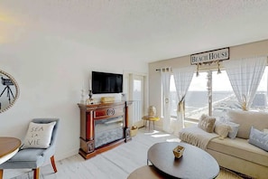 Ein Wohnzimmer mit Fernseher, einer Couch, einem Couchtisch und einem Schild mit der Aufschrift 'Beach House'.