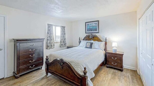 Un dormitorio con una cama de madera, un aparador, una mesita de noche y una ventana con cortinas.