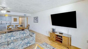 Una sala de estar con un sofá, un televisor montado en la pared y un mueble de madera.