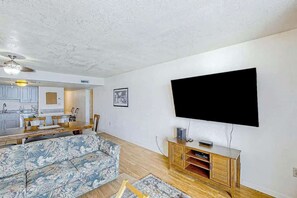 Ein Wohnzimmer mit einer Couch, einem an der Wand befestigten Fernseher und einer Holzkabine.