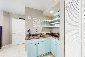 A kitchen with light blue cabinets, a granite countertop, and a built-in oven. - Bay Watch Resort 1901 (North Myrtle Beach)