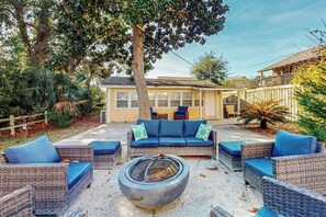 A patio area with wicker furniture, a fire pit, and a house in the background. - Flamingo House 2 - top (North Myrtle Beach)