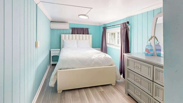 Une chambre à coucher avec un lit, une commode et un miroir.
