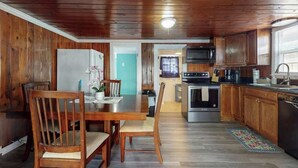 Une cuisine aux murs lambrés, avec une table à manger, des chaises et un réfrigérateur.
