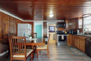 Eine Küche mit Holzwandverkleidung, einem Esstisch, Stühlen und einem Kühlschrank.