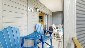 A porch with two blue Adirondack chairs, a white plastic chair, and a wooden bench. A number sign '332' is visible on the wall. - Myrtle Beach Resort A-332 (Myrtle Beach)