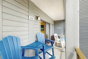 A porch with two blue Adirondack chairs, a white plastic chair, and a wooden bench. A number sign '332' is visible on the wall. - Myrtle Beach Resort A-332 (Myrtle Beach)