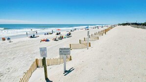 A sandy beach with a wooden fence, beachgoers, and a clear blue sky. - Myrtle Beach Resort A-332 (Myrtle Beach)