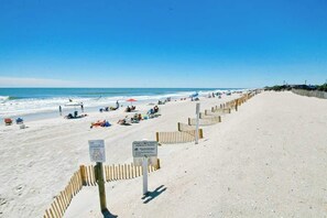 A sandy beach with a wooden fence, beachgoers, and a clear blue sky. - Myrtle Beach Resort A-332 (Myrtle Beach)