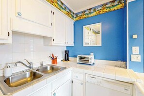 A kitchen with white cabinets, a blue wall, a toaster, and a sink. - Myrtle Beach Resort A-332 (Myrtle Beach)