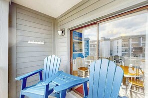 A balcony with two blue Adirondack chairs and a table, overlooking a residential area with houses and a clear sky. - Myrtle Beach Resort A-332 (Myrtle Beach)