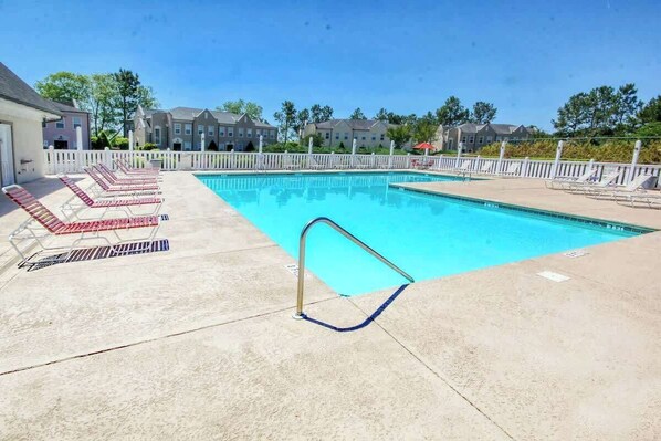 Une piscine avec des chaises longues et une clôture blanche.