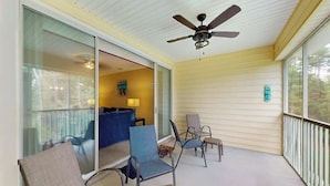 A covered balcony with chairs, a ceiling fan, and a view of the interior. - Legends Resort at Myrtle Beach Unit F (Myrtle Beach)