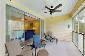 Ein überdachter Balkon mit Stühlen, einem Deckenventilator und Blick ins Innere.