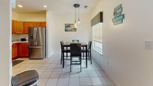 A kitchen with wooden cabinets, a stainless steel refrigerator, and a dining area with a table and chairs. - Legends Resort at Myrtle Beach Unit F (Myrtle Beach)