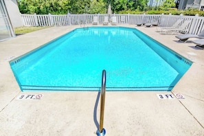 Ein rechteckiger Schwimmteich mit einem Metallgeländer im Vordergrund.