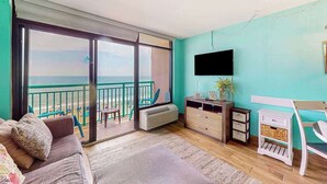 Een kamer met balkon, een bank, een televisie en een tafeltje.