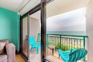 Un balcon avec vue sur la plage, un canapé et deux fauteuils.