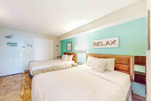 A hotel room with two beds, a 'RELAX' sign, a wooden headboard, a nightstand, and a door with a sign. - Sandcastle South #616 (Myrtle Beach)