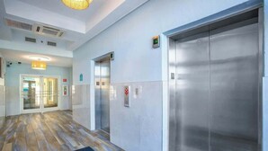 A hotel lobby with a reception desk, a glass door entrance, and a pair of elevators. - Bay Watch Resort 0919 (North Myrtle Beach)