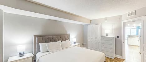 A bedroom with a large bed, a nightstand, a dresser, and a wardrobe.